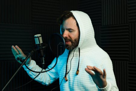 Foto de El apasionado cantante masculino con auriculares actúa en un estudio de grabación con aislamiento acústico - Imagen libre de derechos
