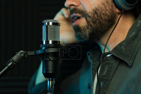 Foto de Vista de cerca de un cantante masculino con barba cantando en un micrófono de estudio - Imagen libre de derechos