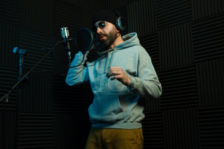 Chanteur masculin branché avec une barbe, se produisant dans un studio d'enregistrement insonorisé
