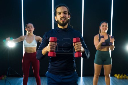 Photo for Motivated group participating in a dynamic workout session with dumbbells - Royalty Free Image