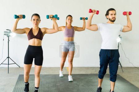 Photo for Three Hispanic people exercising with weights in a fitness class environment - Royalty Free Image