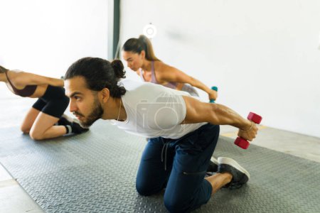 Téléchargez les photos : Instructeurs de conditionnement physique démontrant quelques exercices avec haltères dans un cours de gymnastique - en image libre de droit