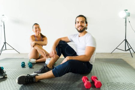 Foto de Sonriendo hombre y mujer tomando un descanso en un estudio de fitness brillante - Imagen libre de derechos