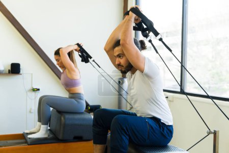 Téléchargez les photos : Séance d'entraînement de reformateur de pilates d'intérieur pour adultes dans une salle de fitness avec un instructeur qualifié - en image libre de droit
