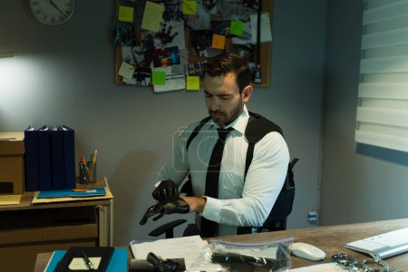 Foto de Detective privado usando guantes y examinando algunas pruebas cruciales en una oficina por la noche - Imagen libre de derechos
