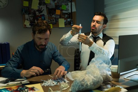 Photo for Two investigators examining shredded pieces of paper and trying to find new clues for a criminal case - Royalty Free Image