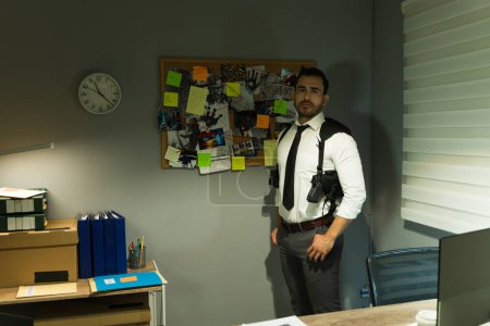 Un enquêteur confiant se tient dans un bureau avec un tableau des preuves la nuit
