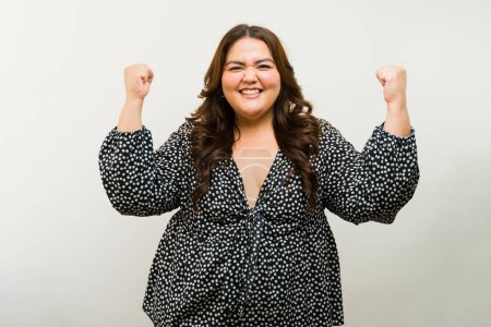 Foto de Mujer alegre de talla grande con los brazos levantados en una alegría contra un fondo de estudio - Imagen libre de derechos
