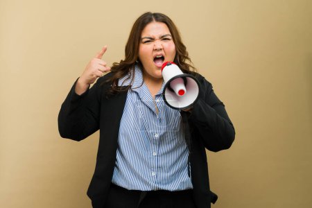 Studio portrait of a curvy woman in professional attire using a megaphone to express herself