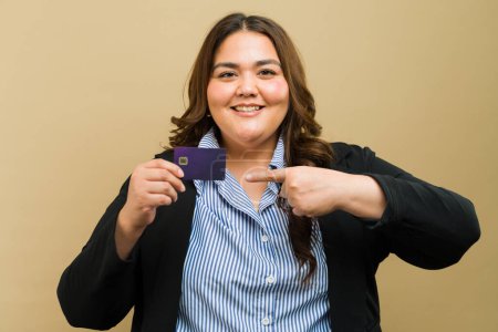 Téléchargez les photos : Portrait d'une jolie femme d'affaires de grande taille tenant une carte de crédit en studio et souriant - en image libre de droit