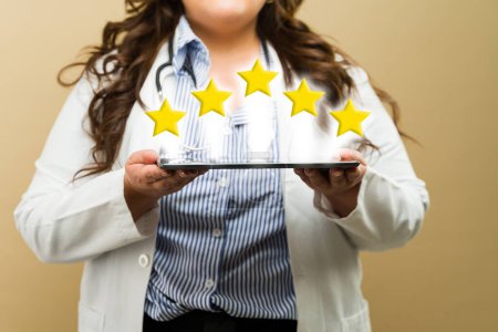 Plus-size female doctor showcasing a five-star review on a tablet, promoting excellent service, seen up close