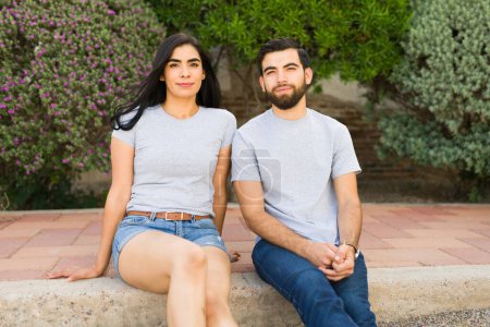 Foto de Hermosa pareja hispana en camisetas grises casuales y vaqueros disfrutando del aire libre con un impresionante fondo natural - Imagen libre de derechos