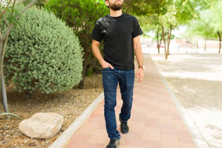 Young hispanic man standing confidently in an urban park setting, wearing a black t-shirt suitable for mock-up designs