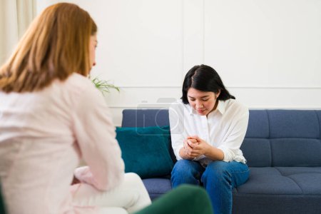Focused psychologist engages with a distressed female patient, providing mental health support in a bright, comfortable therapy room