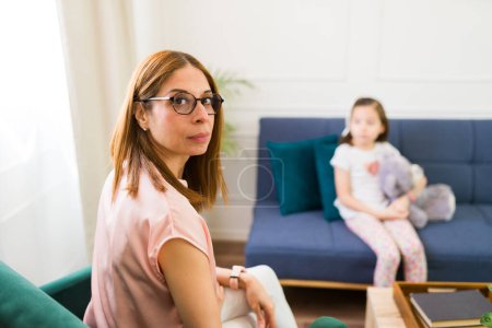 Foto de Professional child psychologist engages in therapy with a little girl sitting calmly with a plush toy in a cozy room - Imagen libre de derechos