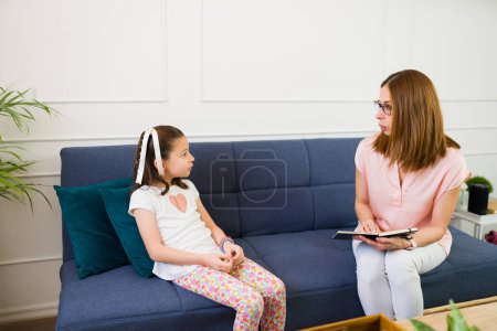 Photo for Caring child psychologist engages in therapeutic communication with a little girl during a counseling session in a bright, modern office - Royalty Free Image