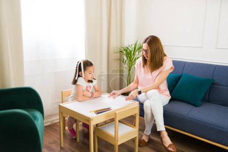 Photo for Professional female psychologist working with a little girl during a therapy session in a bright, welcoming office environment, building trust and communication - Royalty Free Image