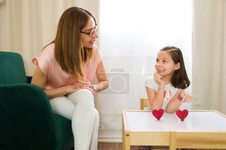 Beautiful little girl pointing at a heart shape and expressing her likes and dislikes with a child therapist