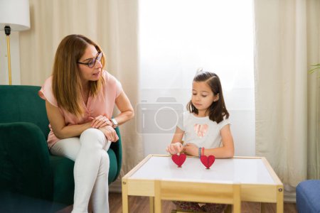 Cute girl points at a heart expressing her likes and dislikes during a therapy session with a psychologist