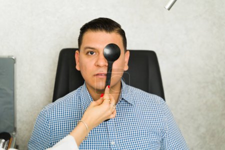 Hand of an ophthalmologist using occluder to assess patient's vision in a clinical setting, ensuring accurate evaluation of eye health and function