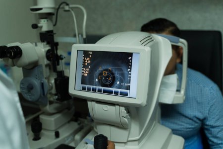 Téléchargez les photos : Professional ophthalmologist is using advanced diagnostic equipment to perform a comprehensive eye exam on a seated patient in a clinic - en image libre de droit