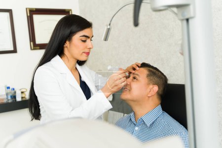 Un ophtalmologiste latin enlève un blocage sur le canal lacrymal d'un patient à l'aide d'une seringue dans une clinique médicale