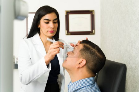 ophtalmologiste professionnel qui nettoie le canal lacrymal d'un patient et vérifie la santé oculaire lors d'un test de vision en milieu clinique