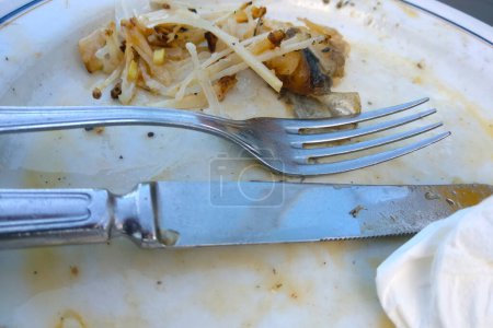 Téléchargez les photos : Vue d'une assiette avec fourchette et couteau après avoir mangé dans un café - en image libre de droit