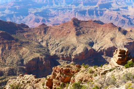 A breathtaking view of the Grand Canyon from the top of a mountain, showcasing the vast expanse of the canyon and the rugged terrain below. The image captures the beauty and immensity of one of the worlds most famous natural wonders.