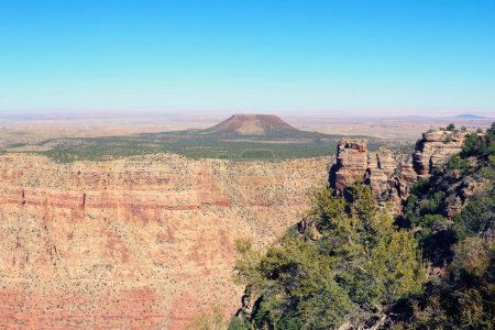 Dieses Foto fängt die Weite des Grand Canyon ein und zeigt seine tiefen Schluchten, schroffen Klippen und farbenfrohen Felsformationen unter klarem Himmel. Der Colorado River schlängelt sich durch den Canyon und trägt zu der dramatischen Landschaft bei.