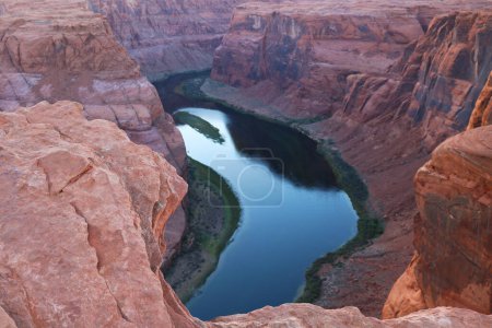 A vast body of water nestled within the deep walls of a canyon, reflecting the surrounding rugged landscape under a clear sky.