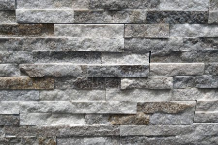 In this close-up shot, a weathered stone wall is prominently displayed. The individual stones show signs of erosion and wear, creating a rugged and textured surface. The mortar holding the stones together is visible, highlighting the craftsmanship of