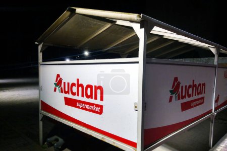 Photo for Wroclaw, Poland, February 15, 2024: A white and red food cart is parked on top of a concrete parking lot. The cart appears to be closed, with no customers around. Auchan chain of stores. - Royalty Free Image