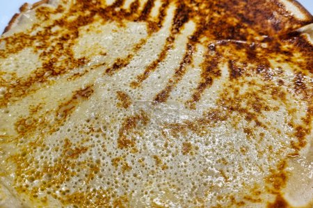 Close-up image of a perfectly cooked pancake with a golden-brown surface and crispy edges, showcasing the intricate texture and inviting appearance. ideal for breakfast or brunch menu design, food blogs, or culinary presentations.