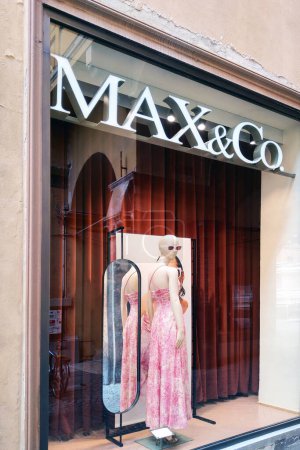 Foto de Florencia, Italia, 10 de mayo de 2024: Un escaparate boutique de moda con un maniquí vestido con un elegante maxi vestido rosa con un patrón floral. la pantalla incluye un espejo arqueado que refleja la vista trasera del vestido, creando un estilo y yo - Imagen libre de derechos