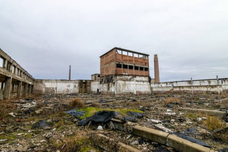 Photo for Inside of an old chemical factory looted dilapidated crumbling. Murky weather. Remains of an abandoned chemical industry factory in shambles. Run down walls in disrepair. Disaster ruins. Cloudy skies and concrete - Royalty Free Image