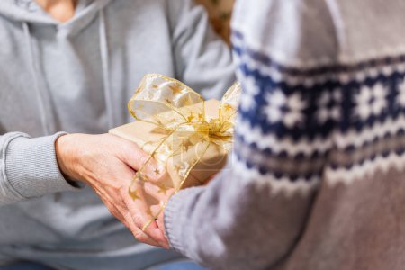 Téléchargez les photos : Closeup of hands of senior woman and a child holding a gift at Christmas - en image libre de droit