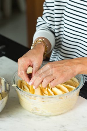 Foto de Woman putting apples while cooking apple pie in the modern kitchen - Imagen libre de derechos