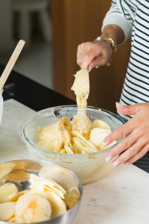 Foto de Woman putting dough in the baking dish while cooking apple pie in the modern kitchen - Imagen libre de derechos