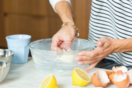 Téléchargez les photos : Woman greasing the baking dish while cooking apple pie in the modern kitchen - en image libre de droit