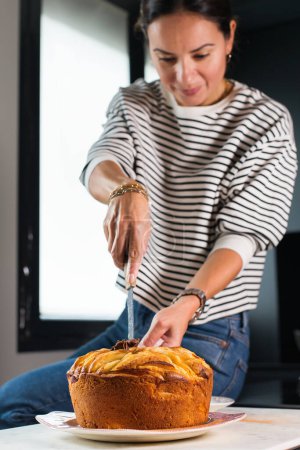 Téléchargez les photos : Young beautiful woman cutting homemade apple pie at the modern kitchen - en image libre de droit