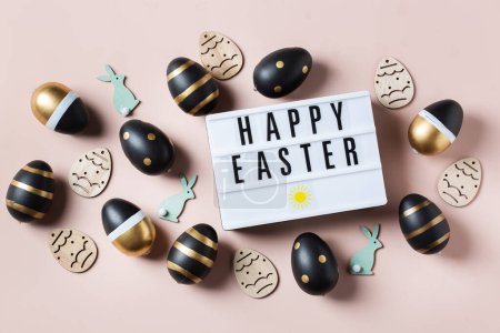 Téléchargez les photos : Joyeux cadre de Pâques avec des œufs dorés, blancs, en pointillés noirs et rayés sur un fond rose. Vue de dessus, plan plat. Carte de vœux de Pâques moderne - en image libre de droit
