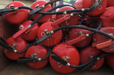 Many red fire extinguishers on the ground. Foam, Carbon dioxide, Powder and Water.Many red powder fire extinguishers with pressure gauge. Detail of fire extinguishers.