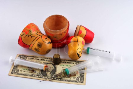A Russian nesting doll with a dollar and a syringe as a symbol of temptation and cunning.The concept of a global drug trafficking network.