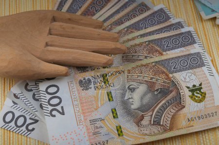 There are many copies of Polish paper money with the wooden hand of an idol on them.Excessive love of money.The concept of the financial crisis.