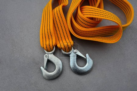 Bracelet de remorquage avec crochets en acier, sur fond gris, vue de dessus. Cordon de sangle de remorquage safety.tow de couleur jaune ou orange avec crochets
