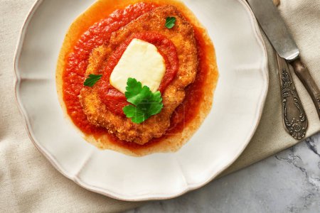 Une assiette de poulet parmigiana avec sauce tomate. Gros plan vue du dessus.