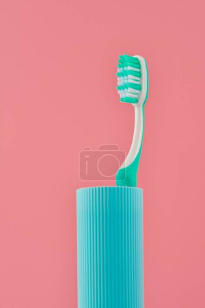 Téléchargez les photos : Image minimaliste d'une brosse à dents turquoise sur un support assorti sur un fond rose. - en image libre de droit