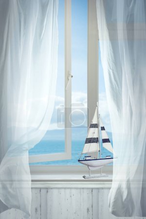 Foto de Ventana abierta con vista al mar y barco de juguete en la repisa de la ventana - Imagen libre de derechos