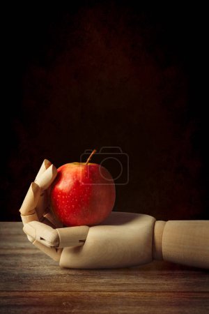 Foto de Mano de artista de madera sosteniendo una manzana roja - Imagen libre de derechos